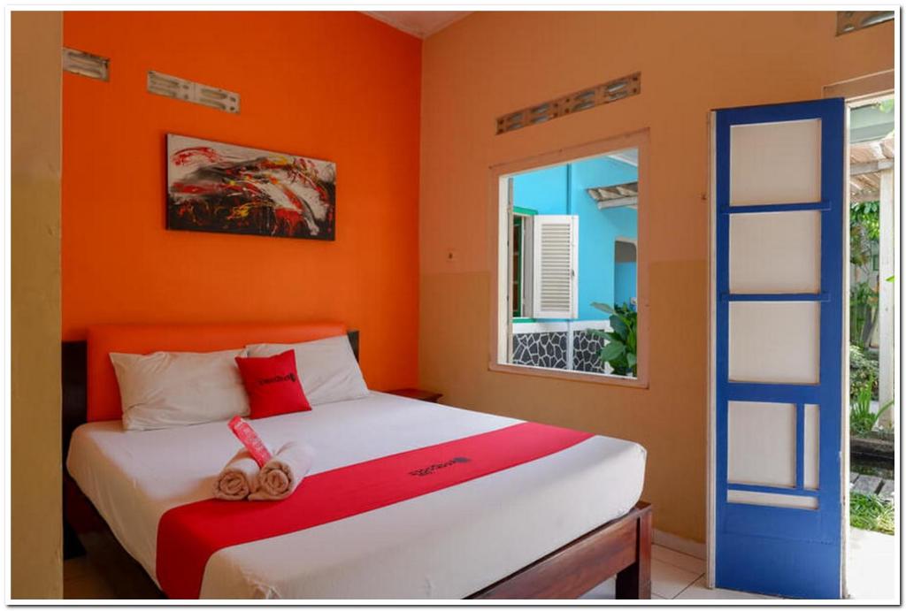 日惹RedDoorz @ Prawirotaman的一间卧室配有一张橙色墙壁的床
