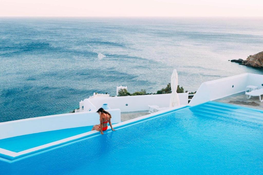 伊奥斯乔拉佩特迪酒店的站在游泳池边俯瞰大海的女人