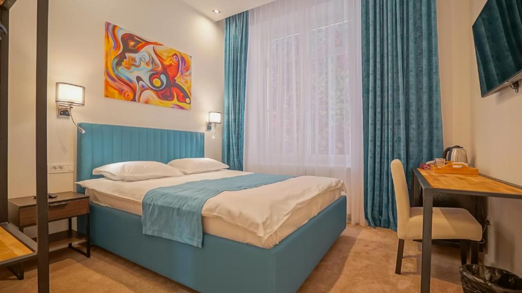 布拉索夫Zoom Rooms的一间卧室配有蓝色的床、一张书桌和一个窗户。