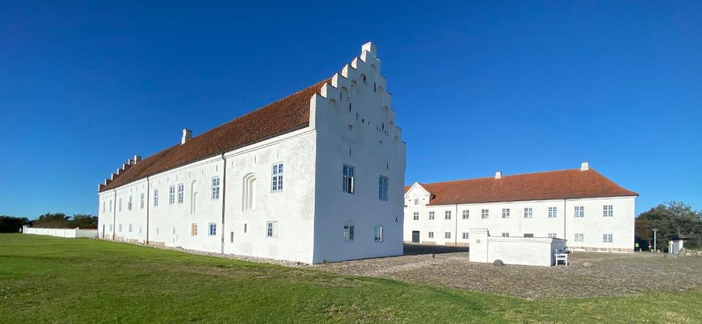 RanumDanhostel Vitskøl Kloster的一座白色的大建筑,有红色的屋顶