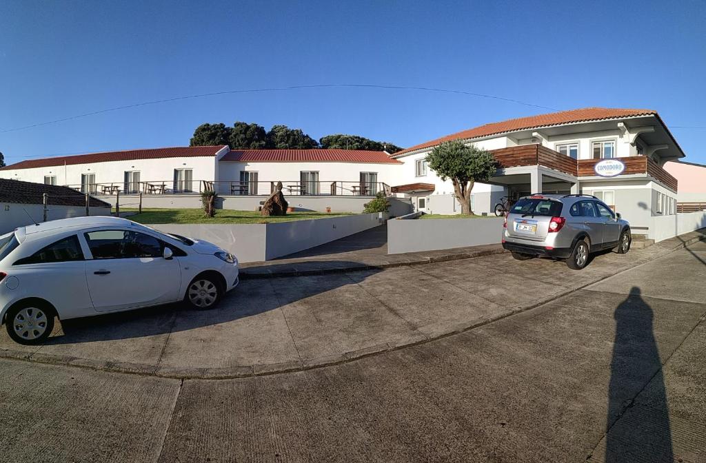 科尔武岛Hotel Comodoro的两辆汽车停在房子前面的停车场