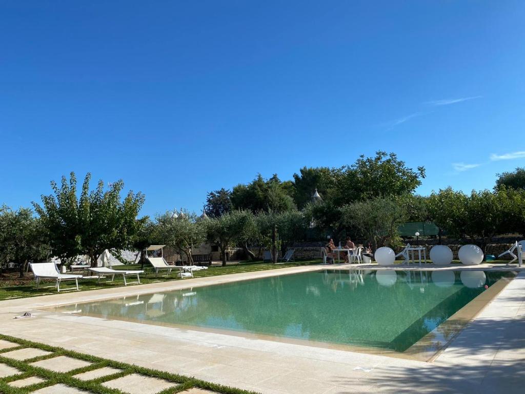 阿尔贝罗贝洛Aria di Casa Country Resort的公园里的一个游泳池,周围的人坐在游泳池周围