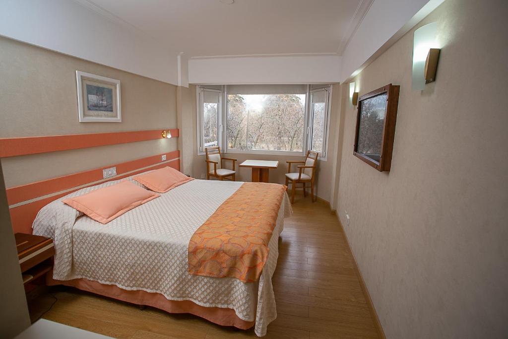 坦迪尔Hotel Dior的一间卧室配有一张床、一张桌子和一个窗户。