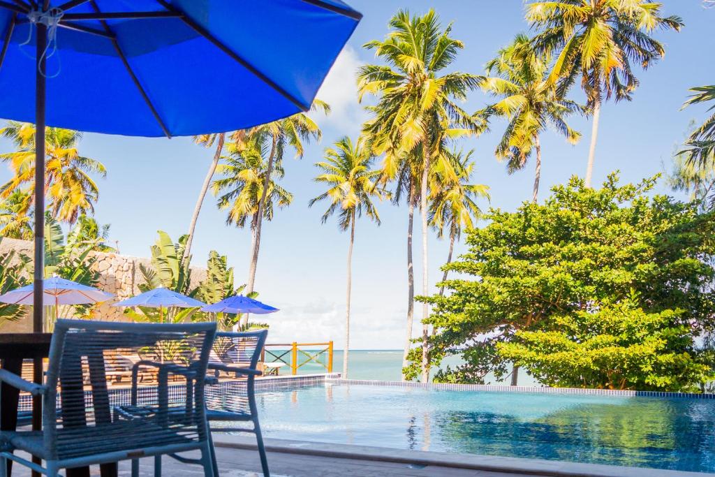 雅帕拉廷加Vila de Taipa Exclusive Hotel的一个带游泳池、椅子和棕榈树的度假村