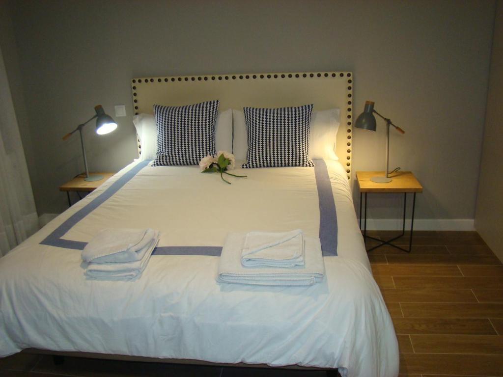 桑坦德Apartamentos La Pereda Santander- Estudio E1的卧室配有白色床、两盏灯和毛巾。