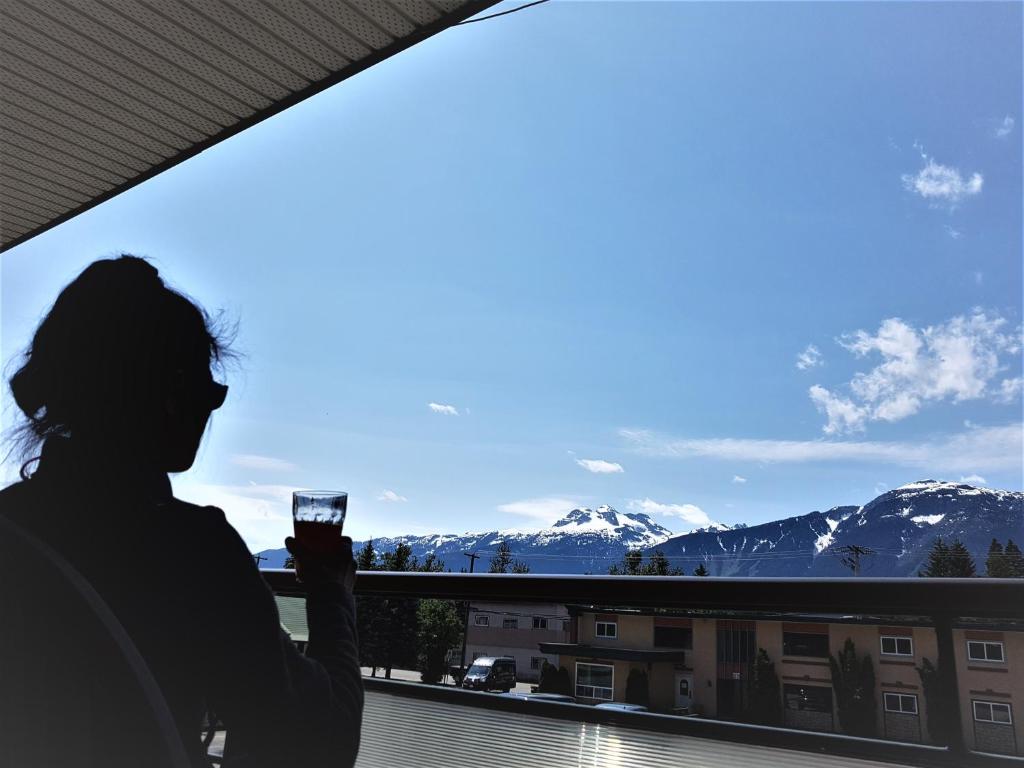 雷夫尔斯托克高山套房酒店的窗户前拿着一杯葡萄酒的女人