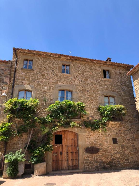 莫奈斯El Palauet de Monells - Adults Only的一座古老的石头建筑,有木门和一棵树