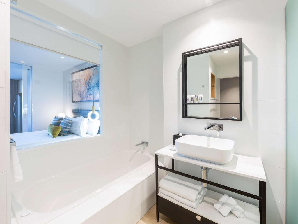 堪培拉Mercure Canberra Belconnen的白色的浴室设有水槽和镜子