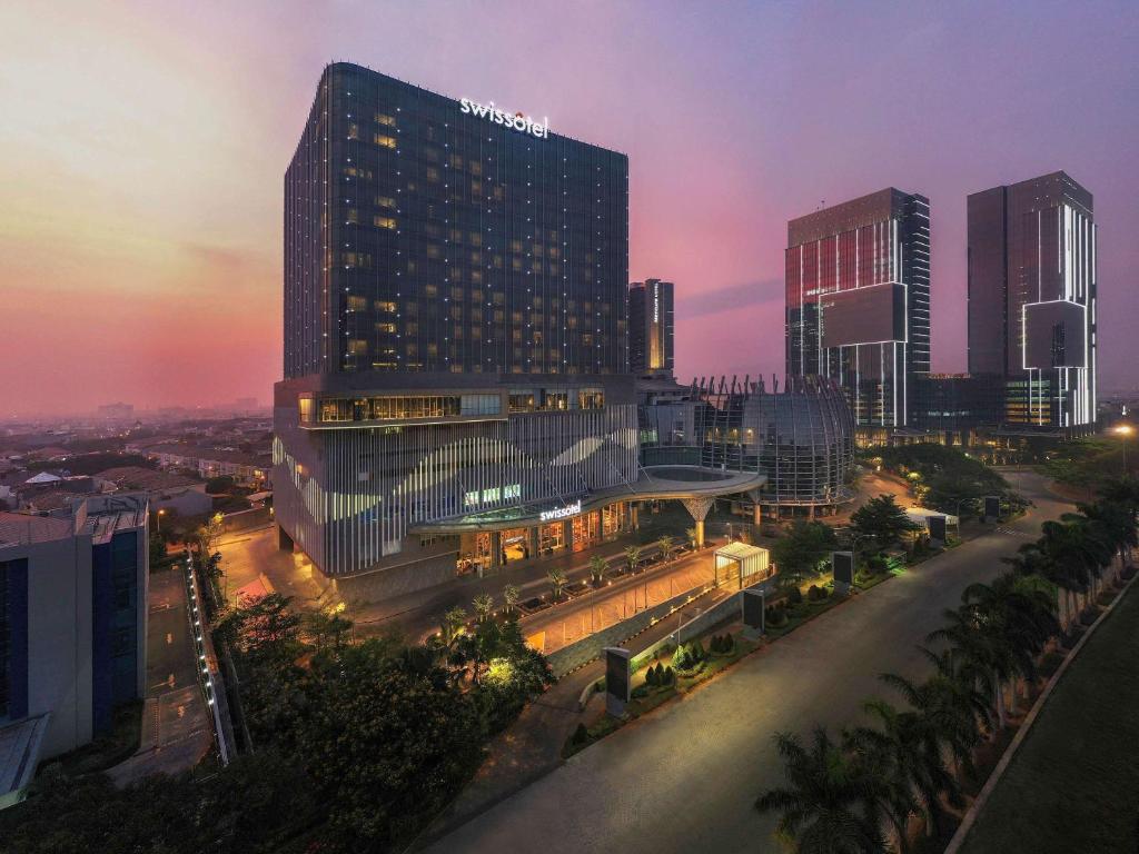 雅加达Swissôtel Jakarta PIK Avenue的城市天际线,在晚上有高楼