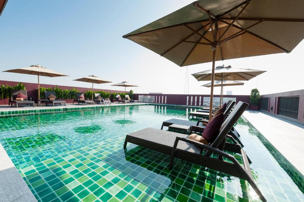 曼谷Casa Nithra Bangkok的一座大楼内的游泳池,配有椅子和遮阳伞