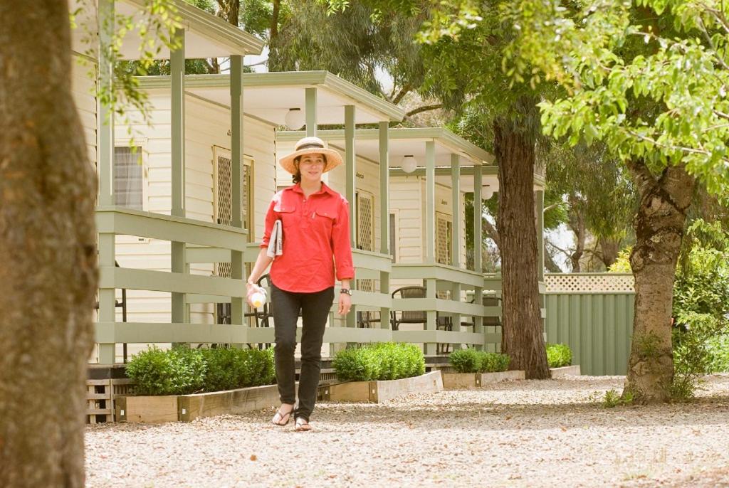 汉密尔顿汉密尔顿湖汽车村和大篷车公园酒店的站在建筑物前身戴帽子的女人