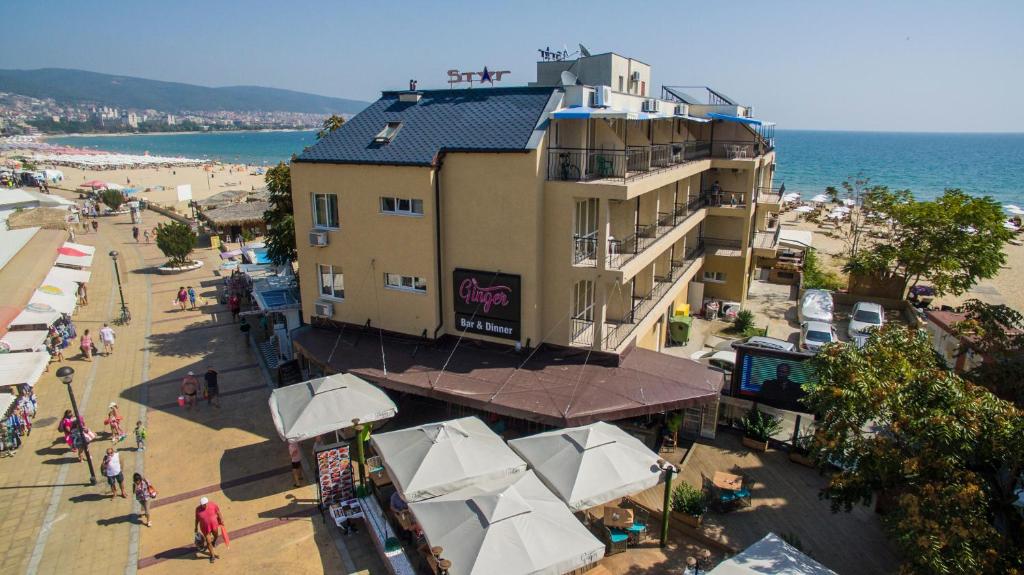 阳光海滩Hotel Star的海滩旁的一座建筑,里面配有人员和遮阳伞