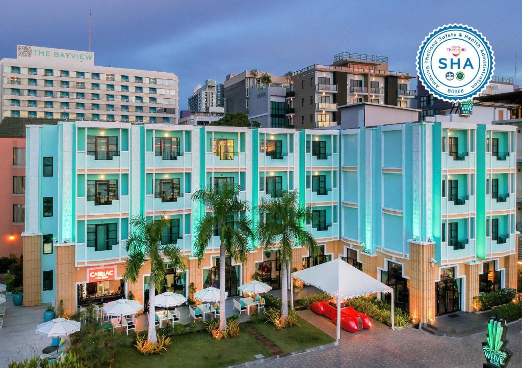 芭堤雅市中心Wave Hotel Pattaya的一座大型蓝色建筑,前面有棕榈树