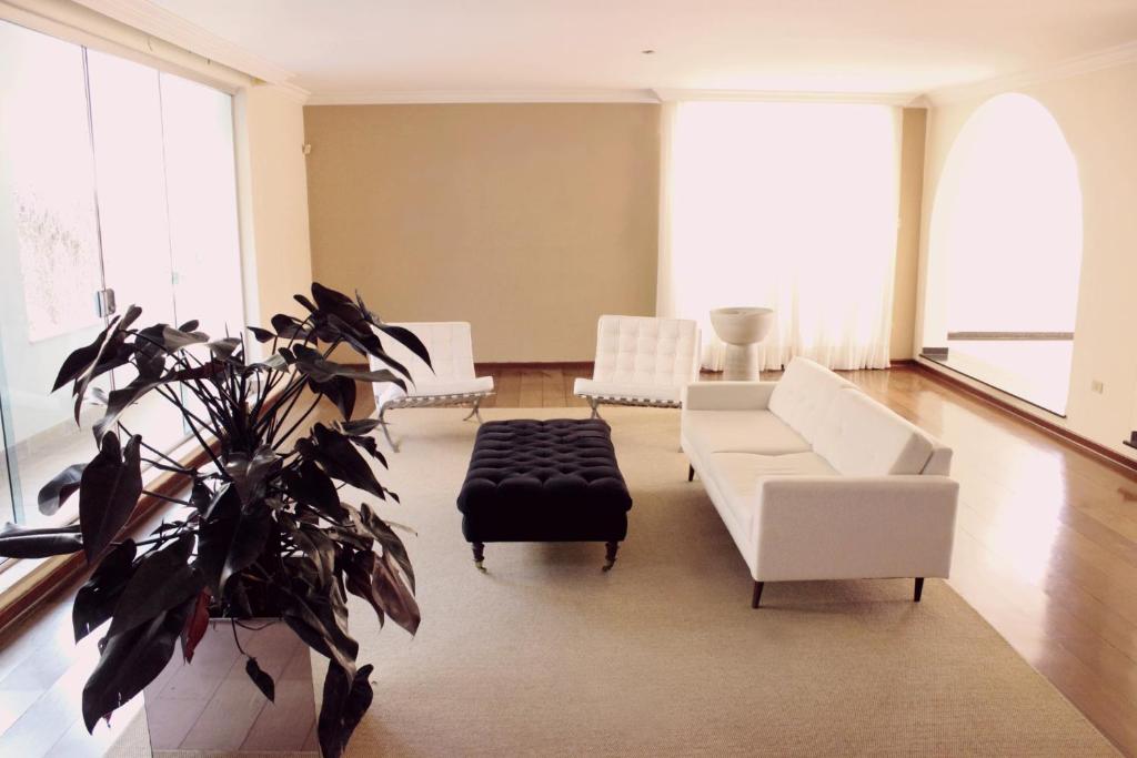 圣保罗Mansão Morumbi 91的一间客厅,配有白色家具和盆栽植物