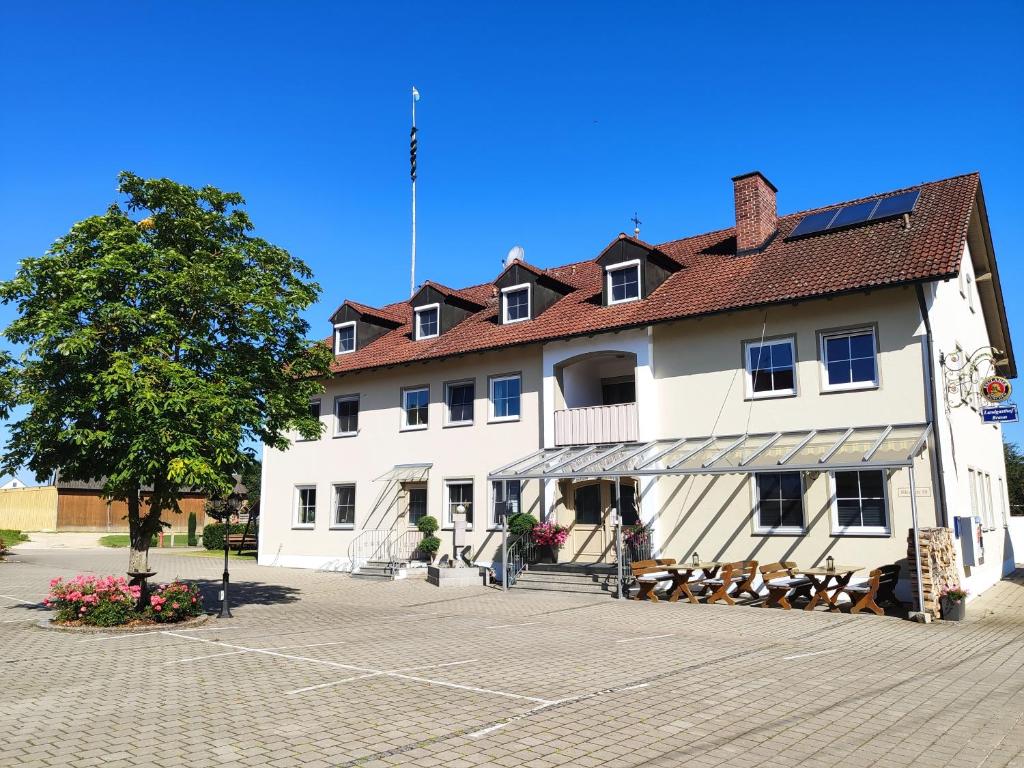 MindelstettenLandgasthof Braun的前面有一棵树的白色大建筑