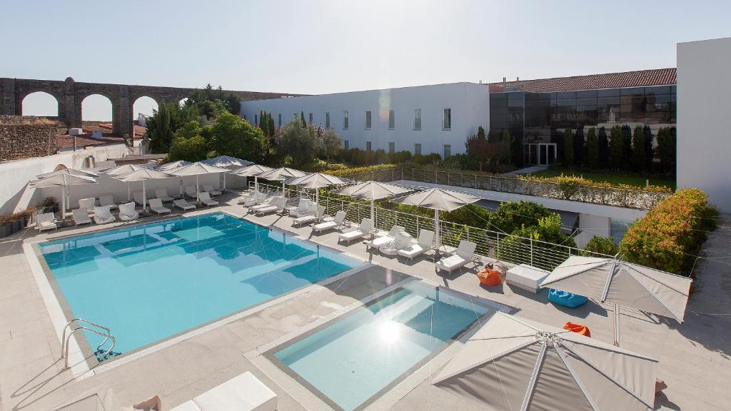 埃武拉马尔德尔阿克度托酒店的享有带椅子和遮阳伞的游泳池的上方景色