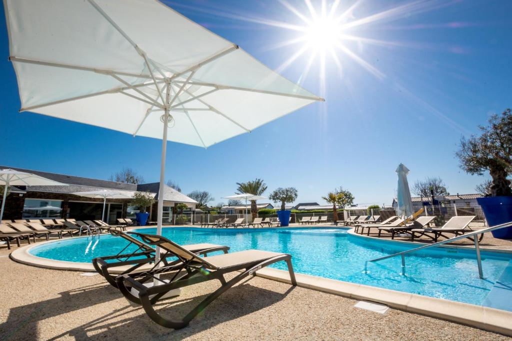 Langrune-sur-MerM&V Resort Camping的一个带椅子和白色遮阳伞的游泳池