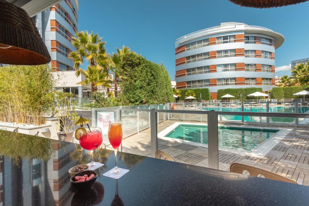 格拉纳达Hotel Abades Nevada Palace的阳台提供2杯饮品和游泳池