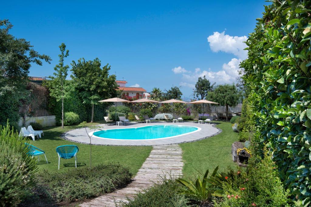 埃尔科拉诺Maison Di Fiore B&B的庭院内的游泳池,配有椅子和遮阳伞
