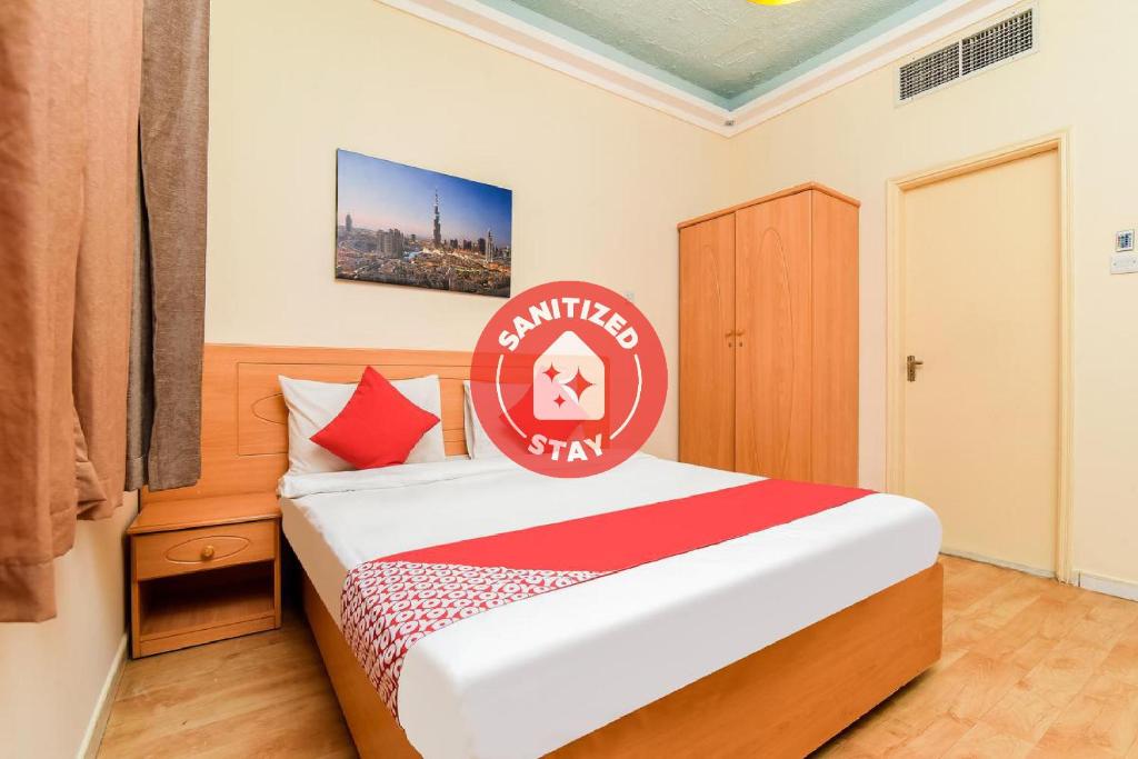 沙迦Sama Hotel的一间卧室,床上有红色标志