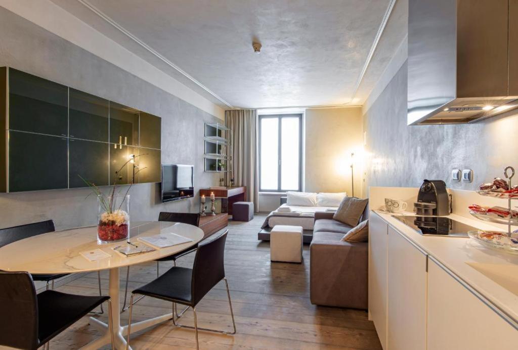 米兰米兰皇家套房中心大教堂公寓的厨房以及带桌子和沙发的客厅。