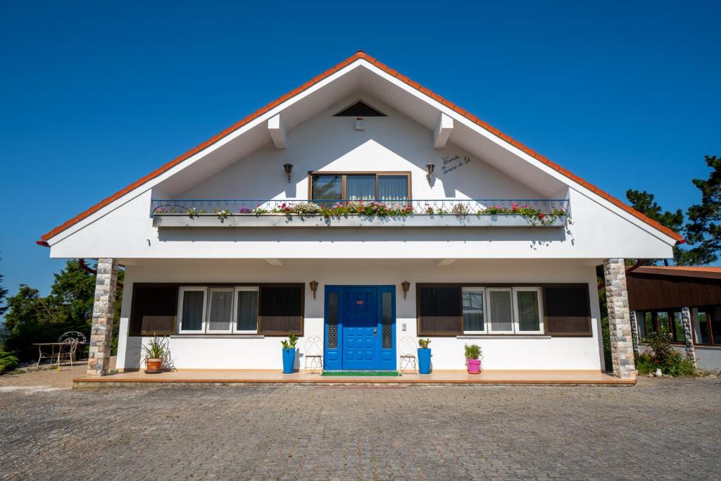 卡尔达斯达·赖尼亚Refúgio Rural - Eco Villa的白色的房子,设有蓝色的门和阳台
