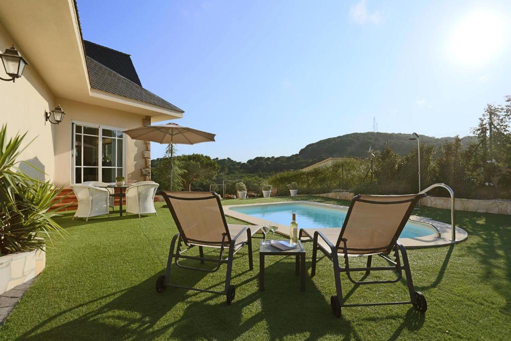 卡里拉Homestay Villa Estrella - Costa Brava的游泳池畔的两把椅子和一张桌子