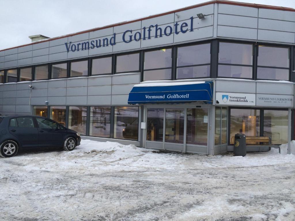 VormsundVormsund Golf Hotell的停在雪地的建筑物前面的汽车