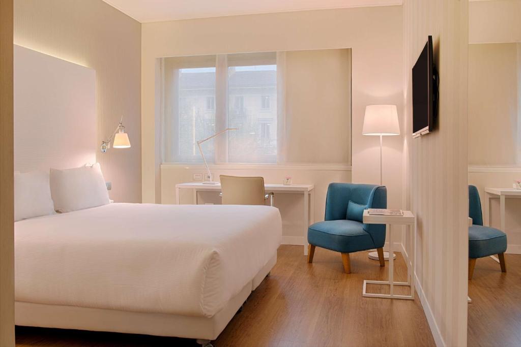 都灵NH都灵中心酒店的酒店客房,配有一张床、一张桌子和椅子