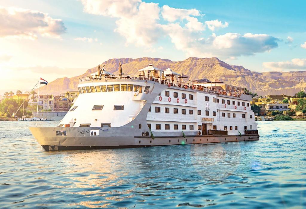 卢克索Champollion II 5 Stars Nile cruise的一艘船在水中,背景是群山