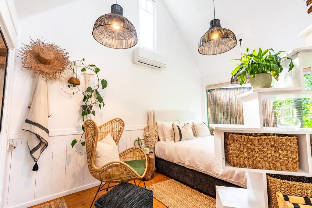 棕榈滩Boho Hill Waiheke Island的一间卧室配有一张床、两把椅子和盆栽植物