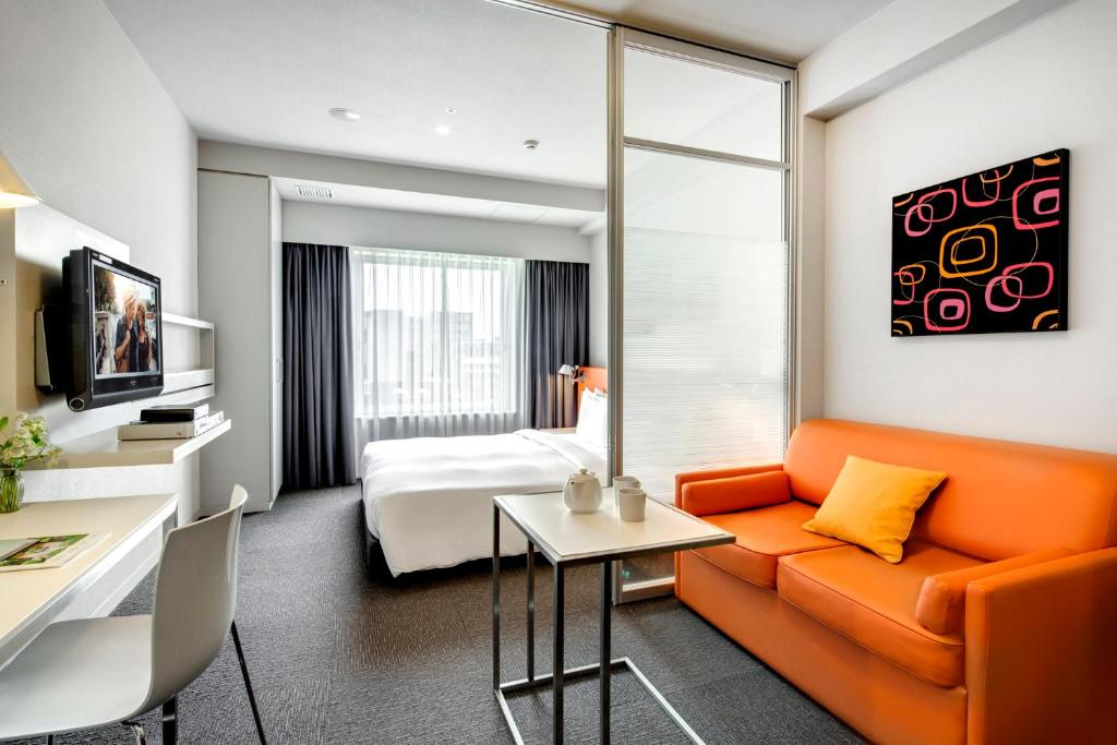 东京东京新宿馨乐庭酒店的酒店客房设有橙色的沙发和一张床