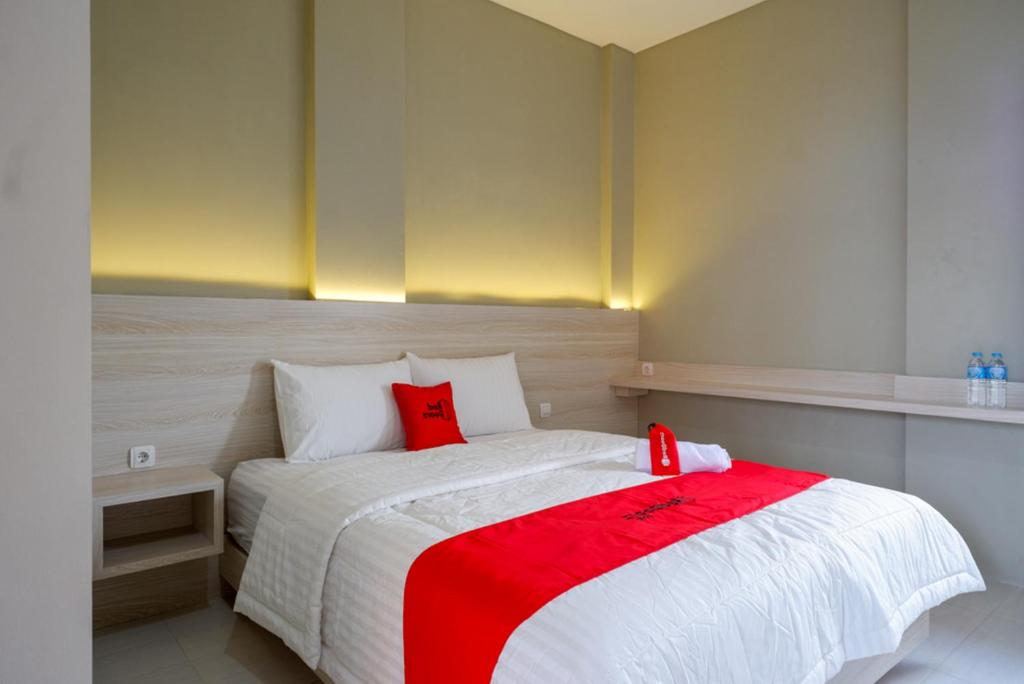 Kalibanteng-lorRedDoorz Syariah near PRPP Semarang的一间卧室配有一张带红色枕头的大床