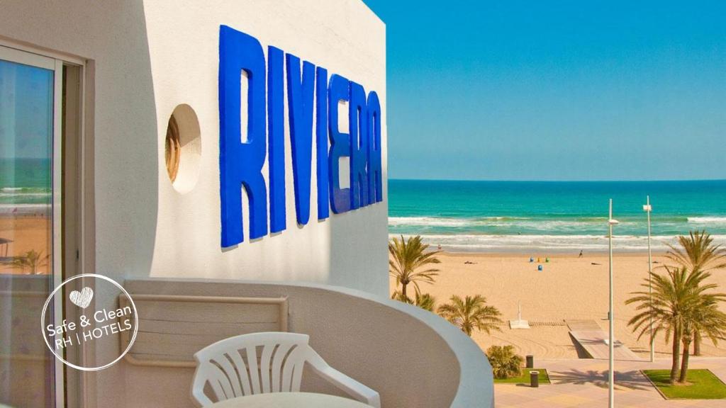 甘迪亚RH里维埃拉酒店 - 仅限成人 的白色椅子的建筑享有海滩美景