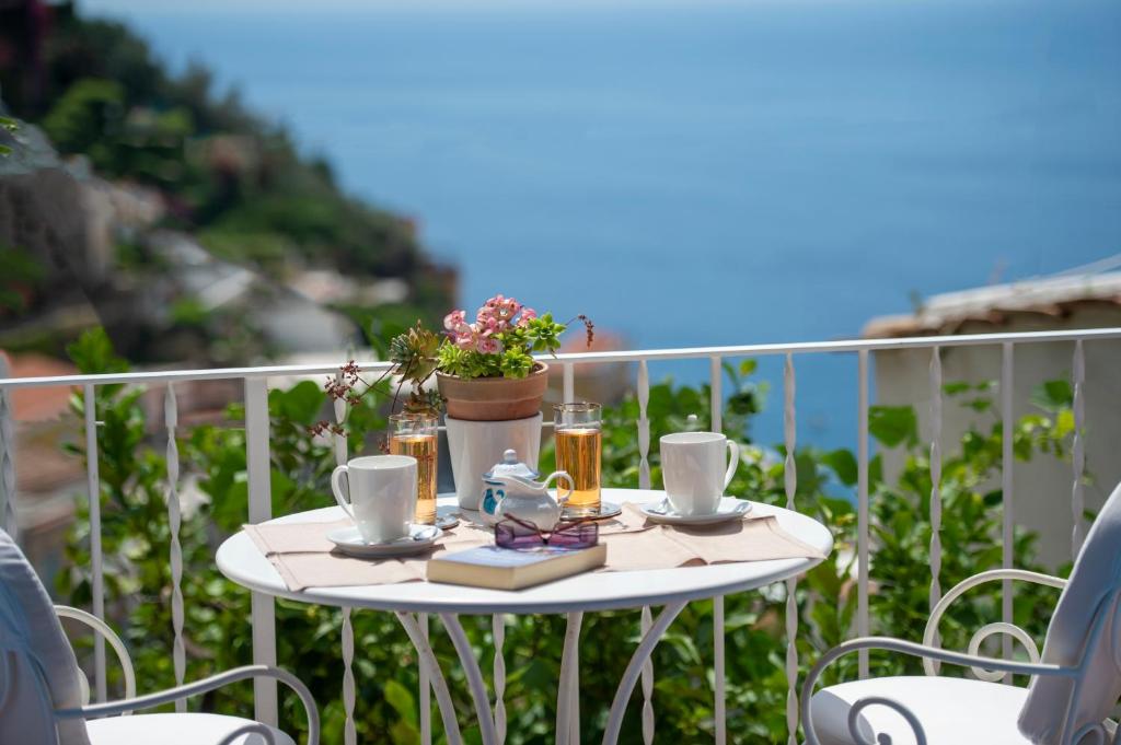 波西塔诺Casa Bellina的阳台上的白色桌子上摆放着饮料和植物