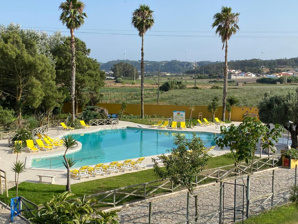 Olho MarinhoCharm Azenha DÓbidos Farm的一座大型游泳池,里面设有黄色的椅子和棕榈树