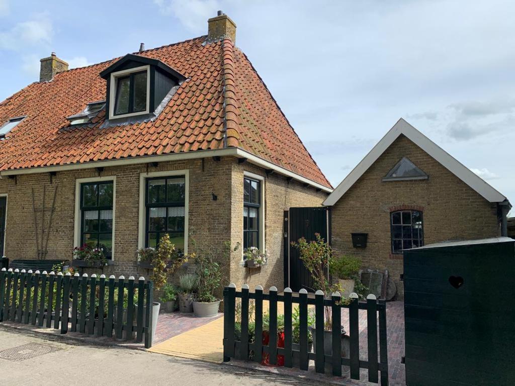 Vakantiehuis in Friesland met boot的前面有围栏的房子