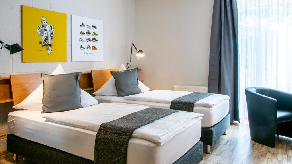 罗拉赫IMPULSIV体育度假酒店的酒店客房,配有两张床和椅子