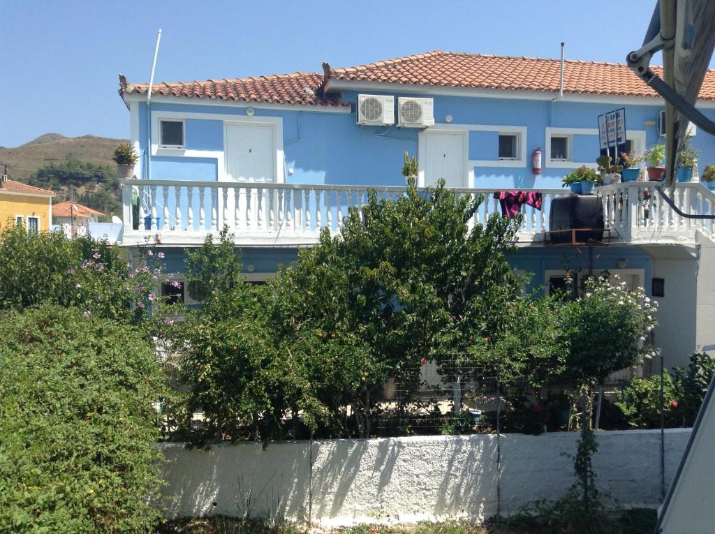 卡拉马孔Dina Studios的蓝色的房子,设有白色阳台和树木