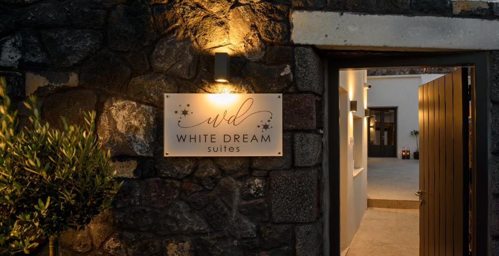 费拉White Dream Suites的石墙上的白色梦幻套房的标志