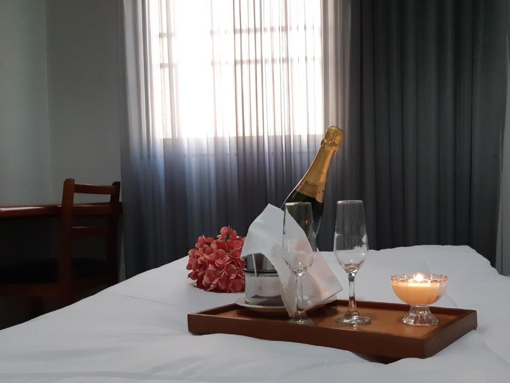 阿拉瓜伊纳Hotel Executivo的床上的一瓶香槟和两杯酒