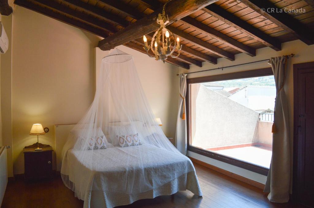 卡米诺新村Casa Rural La Cañada的一间卧室配有一张带吊灯和窗户的床。