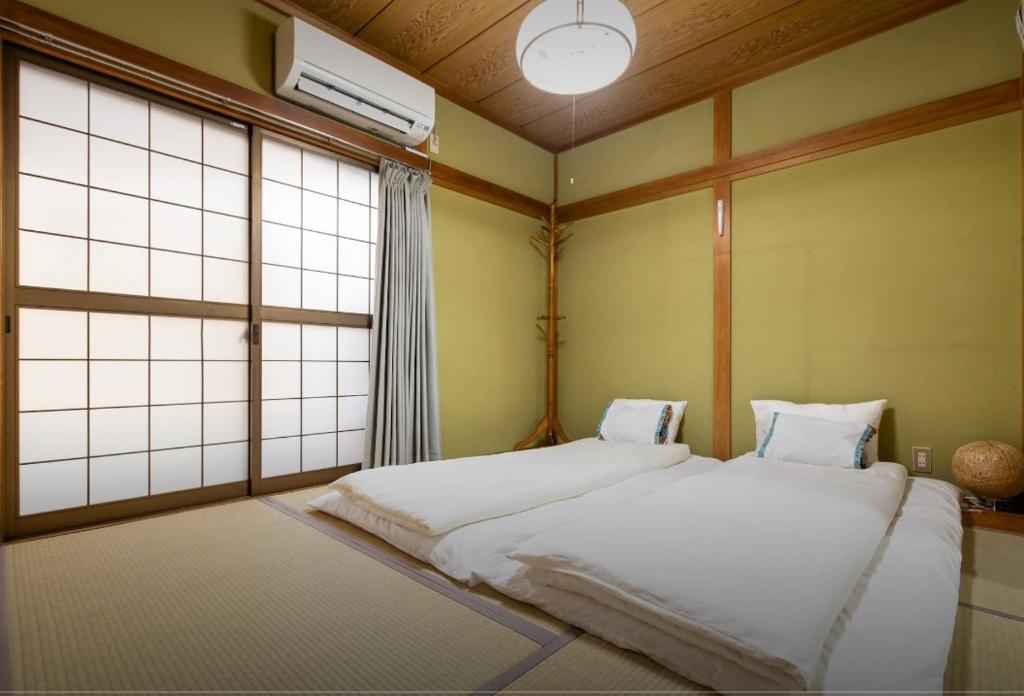 大阪10mins train to Namba, 4 mins walk to stn, 2 floors japanese style , 2-8 people的一间卧室设有两张床和窗户。