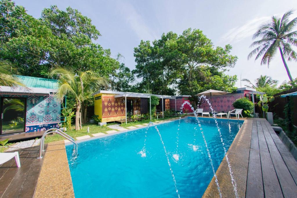 珍南海滩Tisha Langkawi Wellness Resort的一座带木甲板的游泳池,位于一座房子旁边