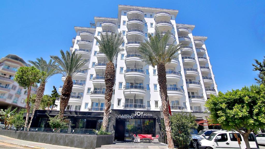 阿拉尼亚Ramira Joy Hotel的一座白色的建筑,前面有棕榈树