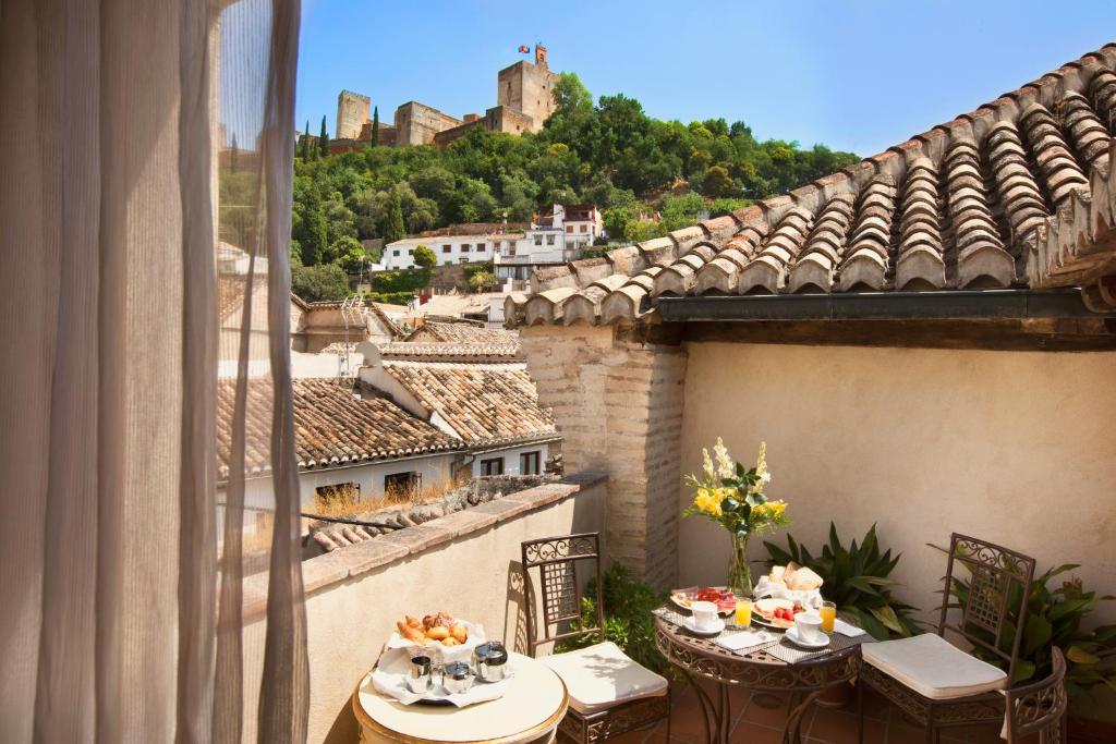 格拉纳达格拉纳达卡萨1800酒店的阳台配有桌子,享有城堡的景色