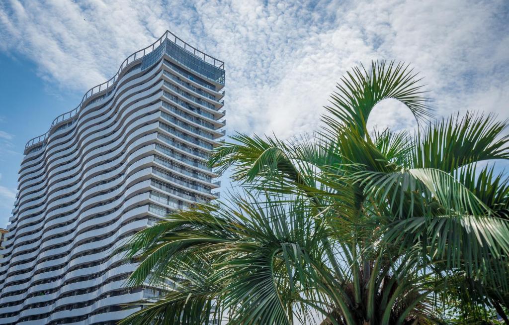 巴统Orbi Residence Hotel Official的一座高大的建筑,前面有棕榈树