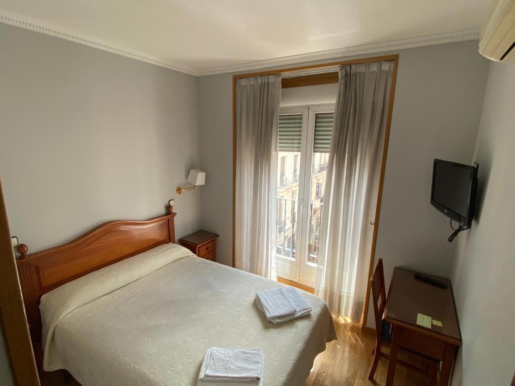 马德里格拉旅馆的一间卧室配有一张床、一台电视和一个窗口