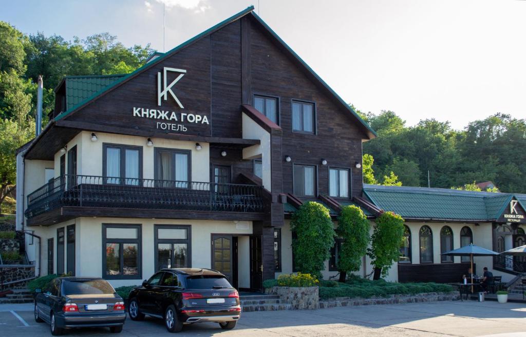 卡尼夫Knyazha Hora Hotel的门前有车辆停放的酒店