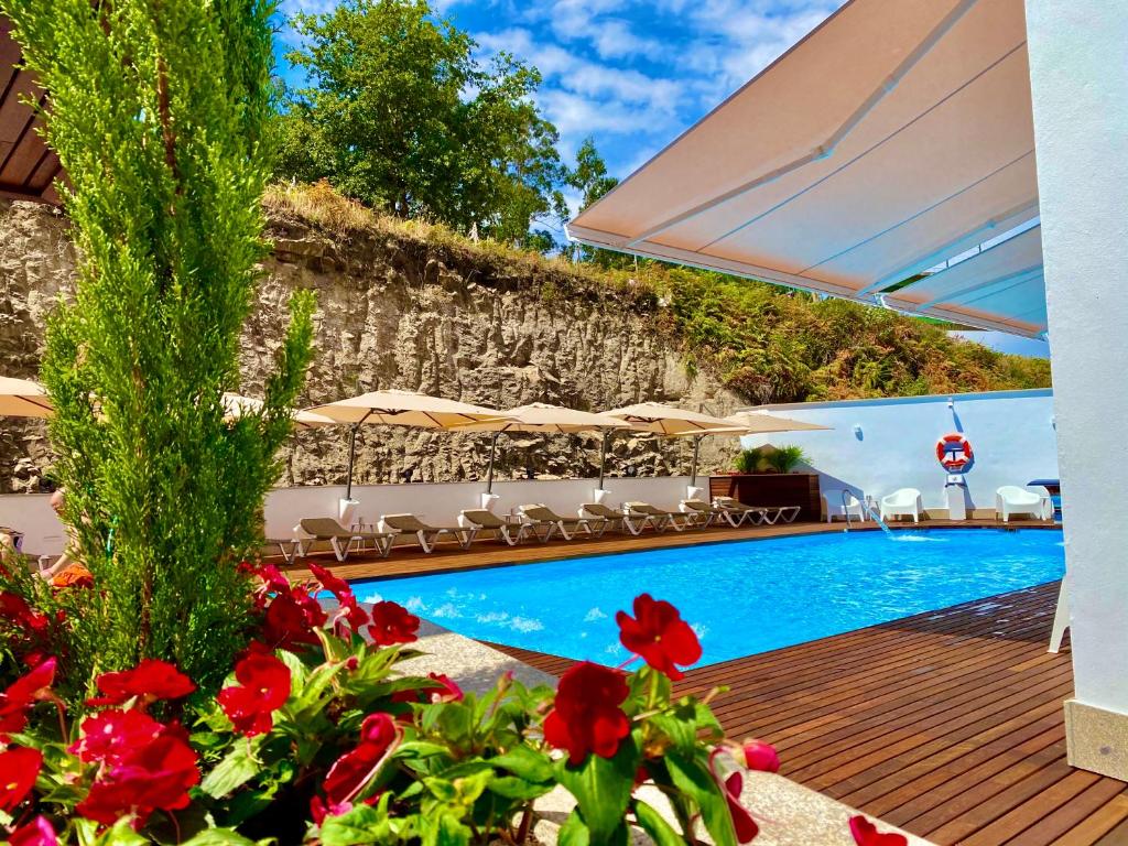 CatoiraHarpazul的一座拥有红色鲜花和遮阳伞的游泳池